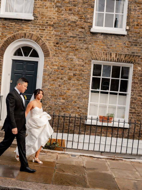 A couple walk down a street in wedding attire in central London