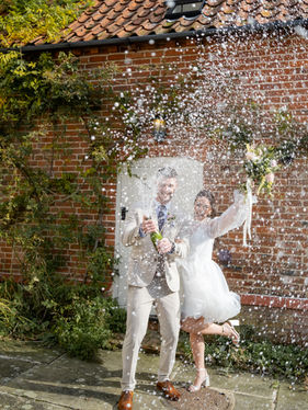 A couple pop a champagne bottle on a wedding day 