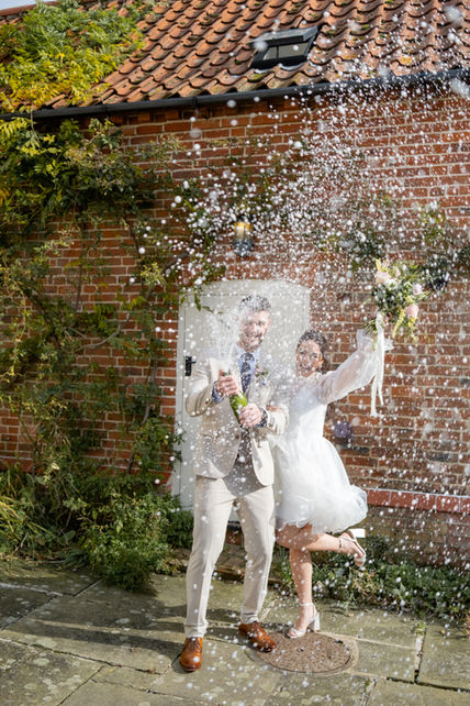 A couple pop a champagne bottle on a wedding day 