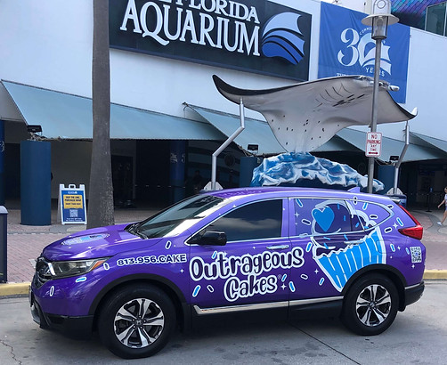 Image of Outrageous Cakes delivery vehicle parked outside The Florida Aquarium in Tampa, showcasing local custom cake delivery service