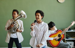 happy-youthful-schoolgirl-with-microphone-performi-2023-11-27-04-57-41-utc