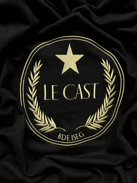Broderie dorée sur noir, emblème avec étoile et lauriers, texte « LE CAST - BDE ISEG ».