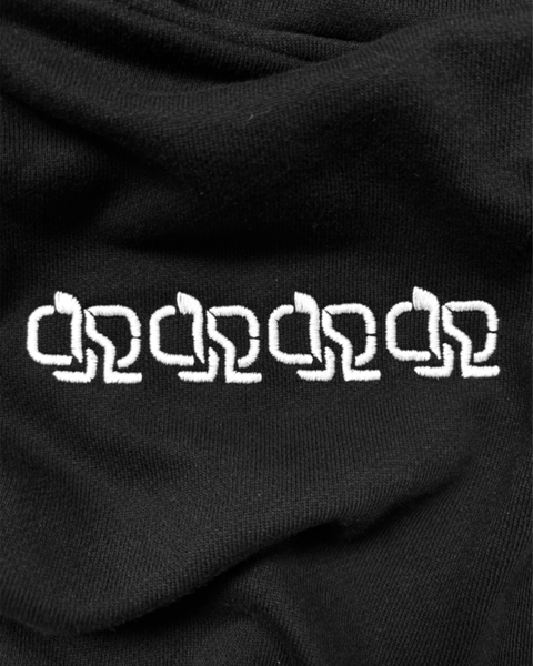 Détail sur broderie blanche répétée en chaîne sur hoodie noir.