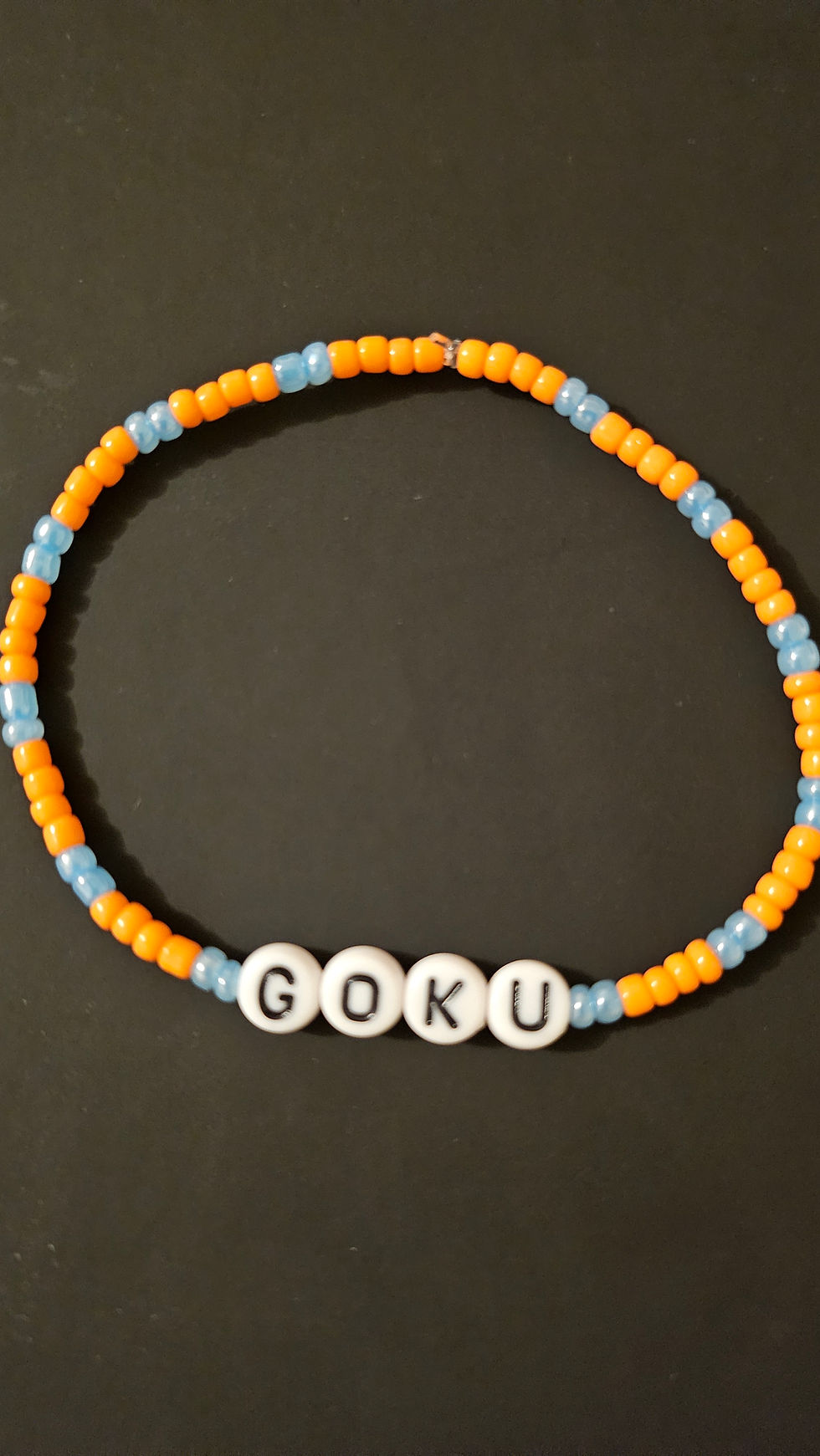 Bracelet coloré avec le mot GOKU, bijoux fantaisie, perles bleues et oranges.