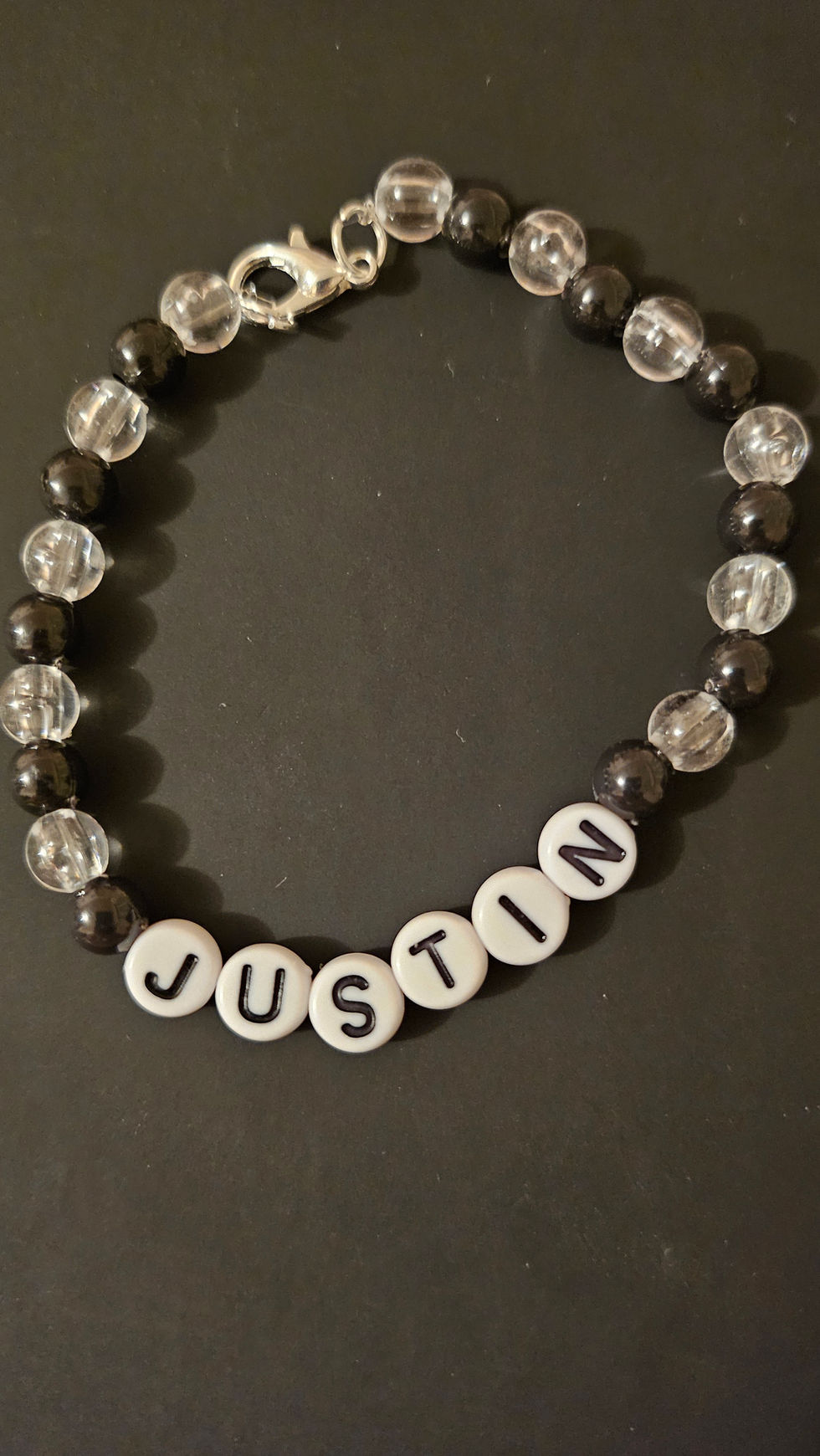 Bracelet de perle noirs et transparent avec le prénom JUSTIN, Kissbijoux. background.