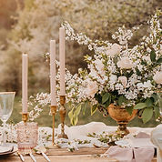 Beautiful flowers in a vase with long candlesticks and place settings.
