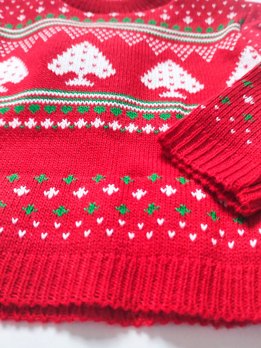 Red Christmas jumper with white trees, and green & white patterns.