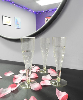 Private Party Champagne glasses sit on a table surrounded by rose petals