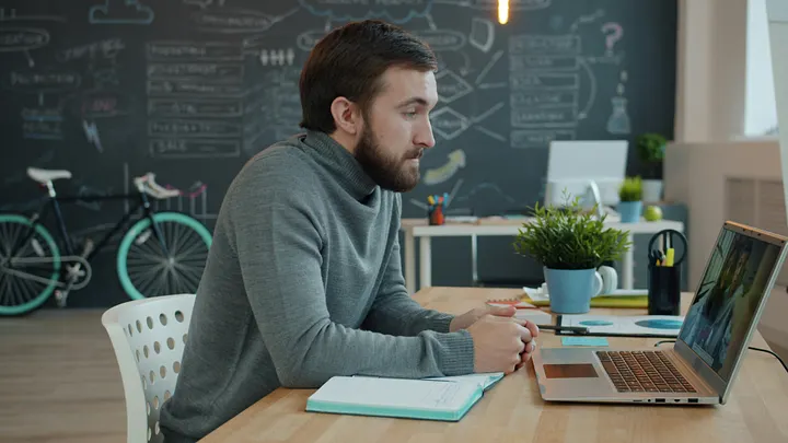 Man sitting at desk looking at laptop screen