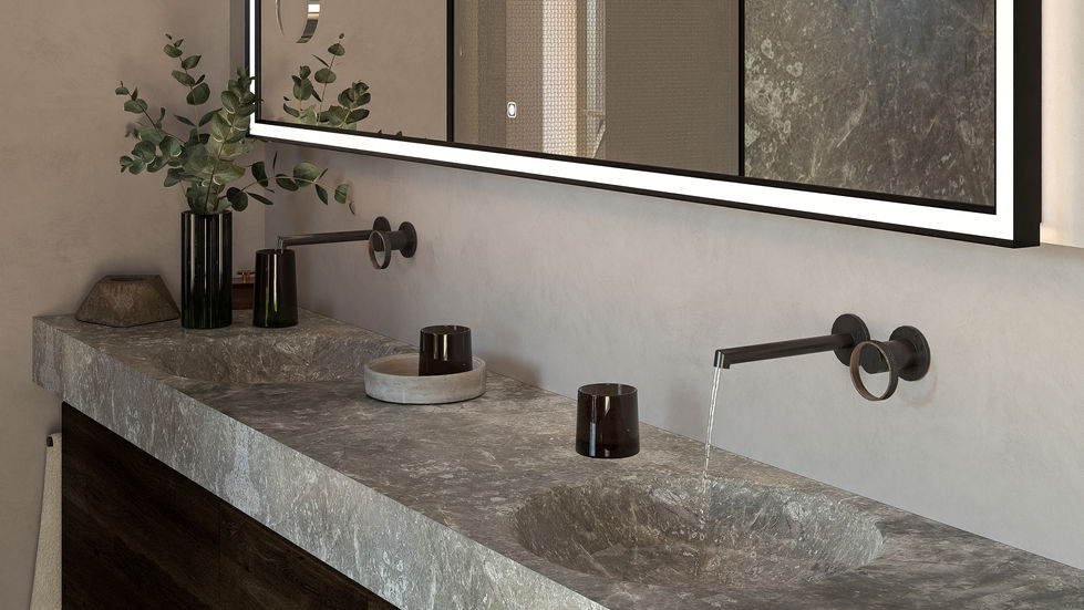 Custom natural stone vanity with carved basins, wall-mounted fixtures, illuminated mirror, and luxury contemporary bathroom detailing.