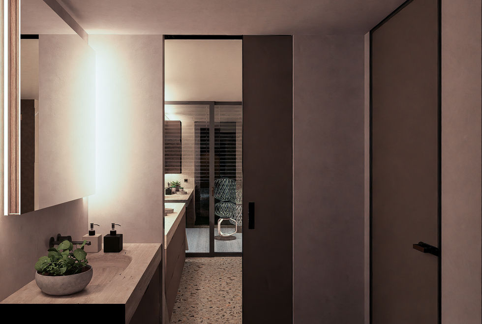 Luxury family bathroom featuring a custom double vanity, integrated lighting, geometric wall panels, and mirrored twin shower