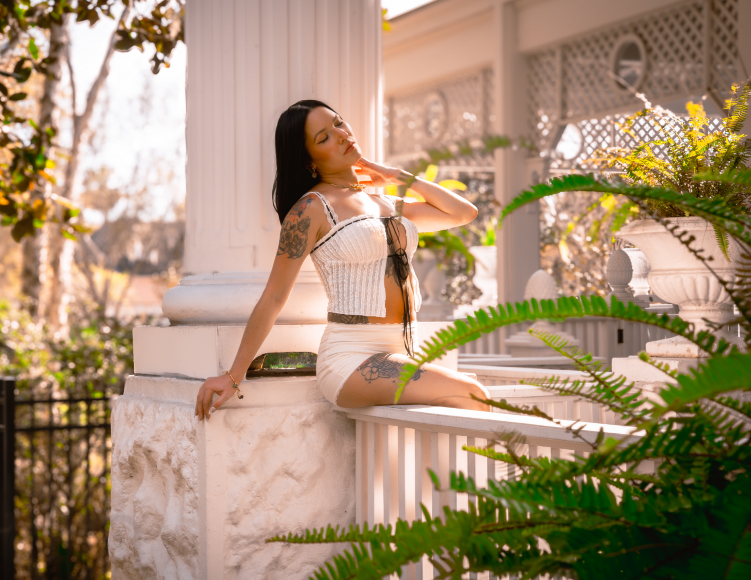 Model in white outfit relaxing on a white porch railing