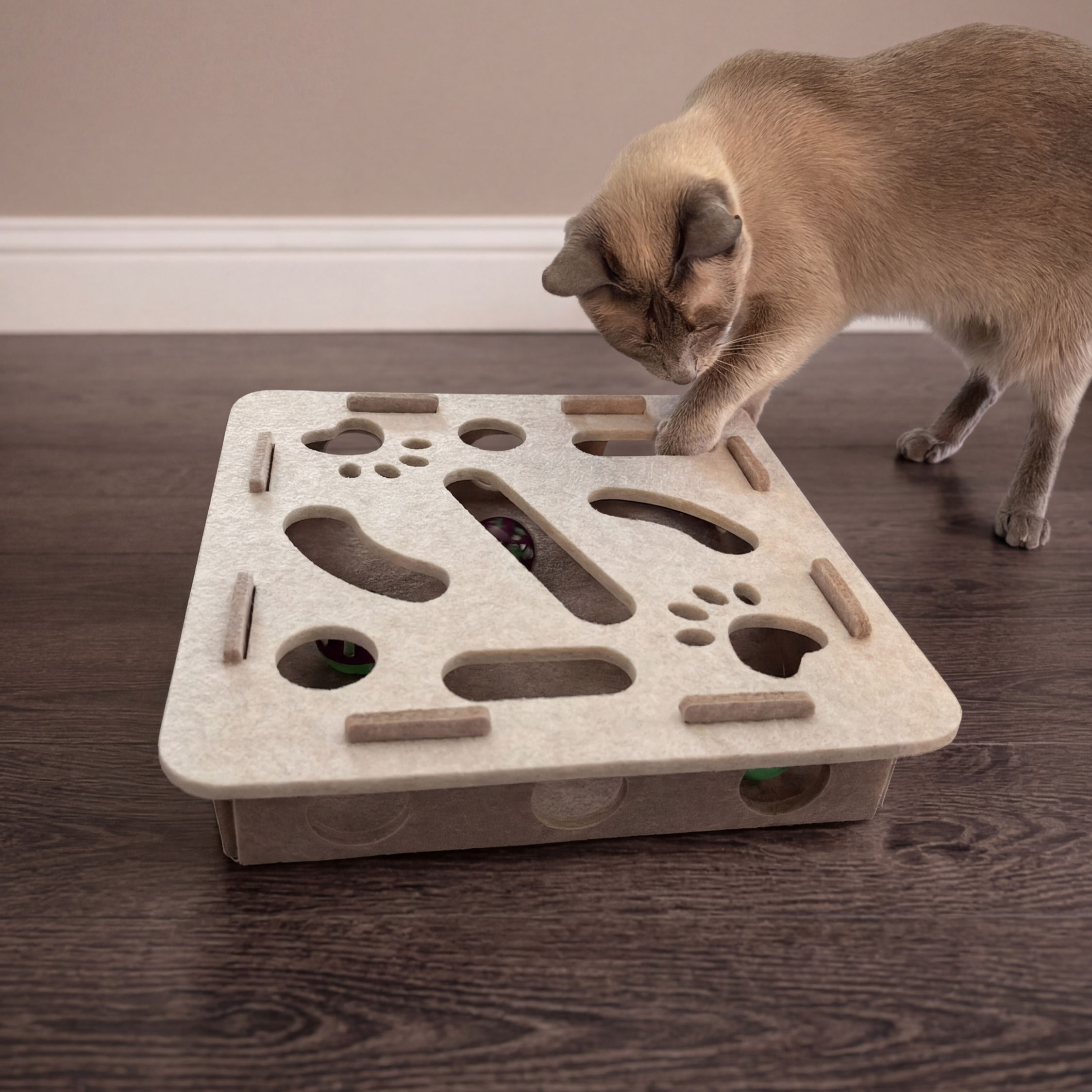 Siamese cat pawing through holes in felt brain training puzzle box