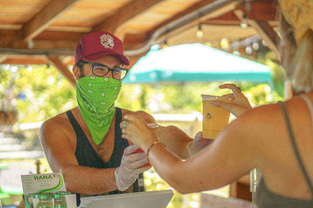 Hana Farms Roadside stand team member hands customer fresh fruit soda