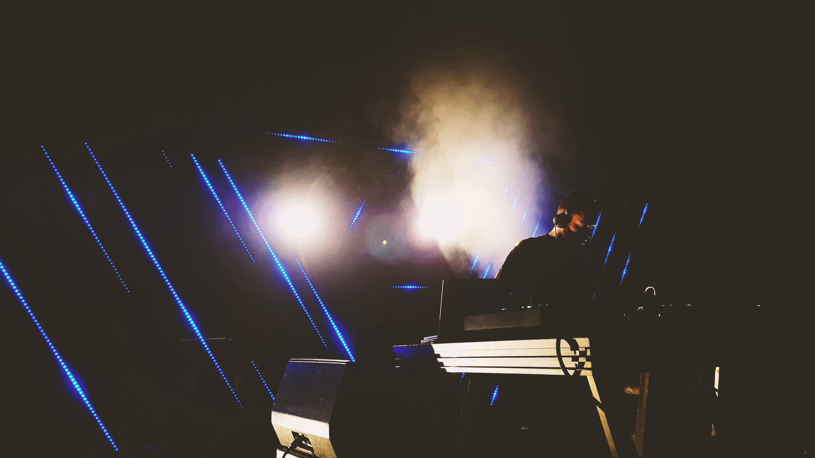 A DJ performing on a stage with bright lights and smoke effects.
