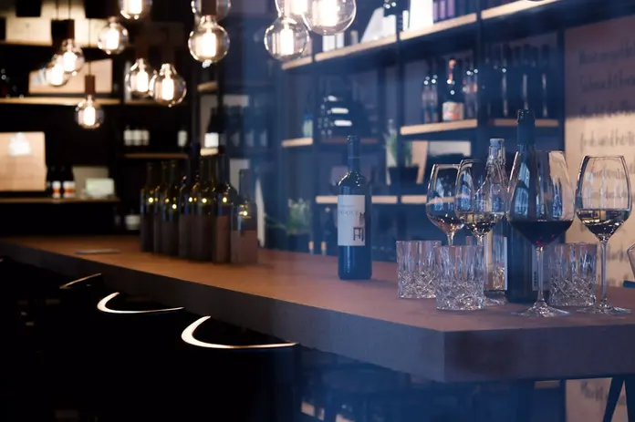 Blick durch das Schaufenster der Vinothek Hauser bei einer Degustation mit Rotwein in der Weinhandlung in Luzern.