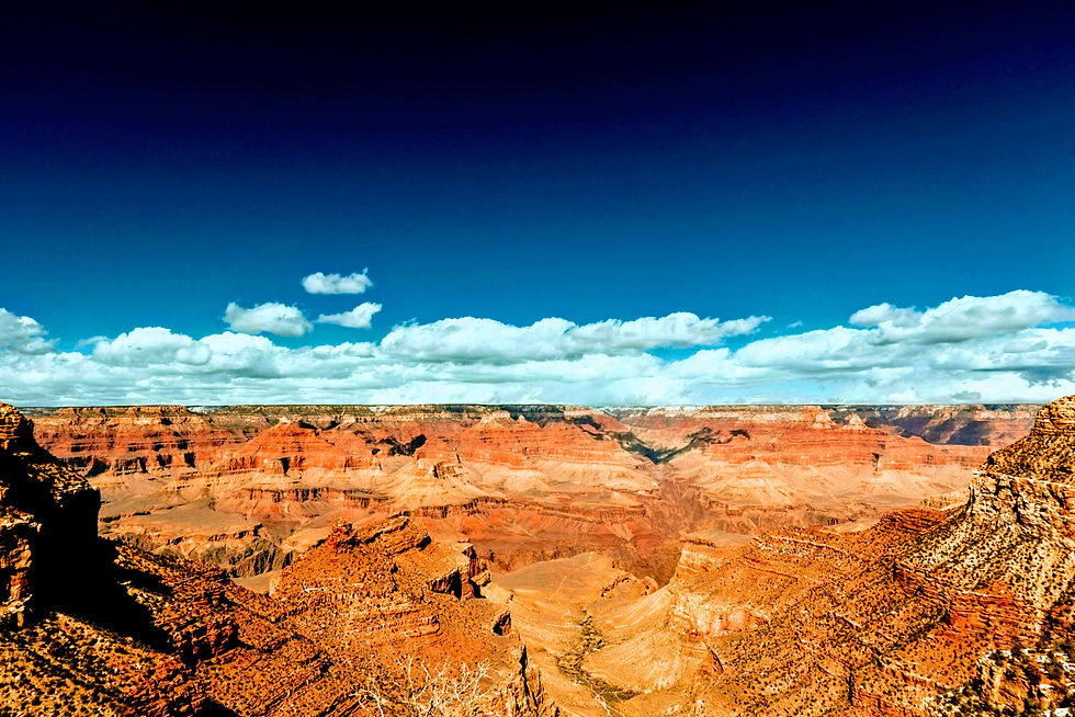 Grand Canyon landscape with vibrant orange cliffs under a deep blue sky and fluffy clouds, creating a majestic and serene scene.