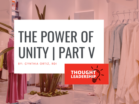 Modern retail clothing store interior with soft pink and neutral tones. Clothing racks display light-colored garments including dresses and tops. Large leafy plants in planters are positioned throughout the space, and natural light filters through windows. White text overlay reads 'THE POWER OF UNITY | PART V' by Cynthia Ortiz, RDI, with a red 'THOUGHT LEADERSHIP' badge featuring a lightbulb icon in the bottom right corner.