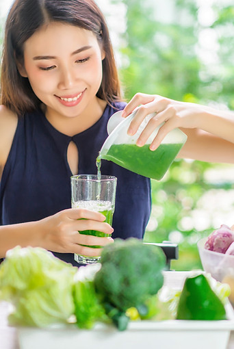 Young Asian Woman Happy Drinking Fresh Green Detox Vegetable Juice. Healthy detox vegan di