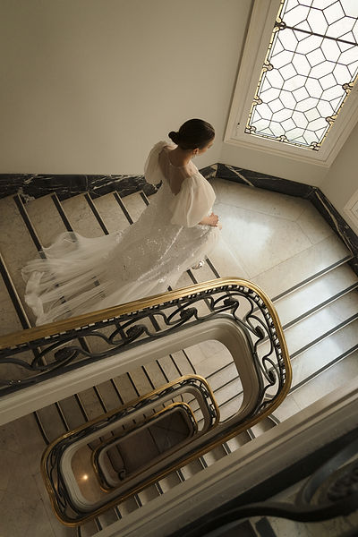 Plano cenital de novia bajando escaleras de mármol con vestido diseñado por Leyre Valiente