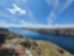Vast blue river with rocky cliffs under a clear sky. Wispy clouds stretch across, creating a tranquil and open atmosphere. Columbia River, Washington