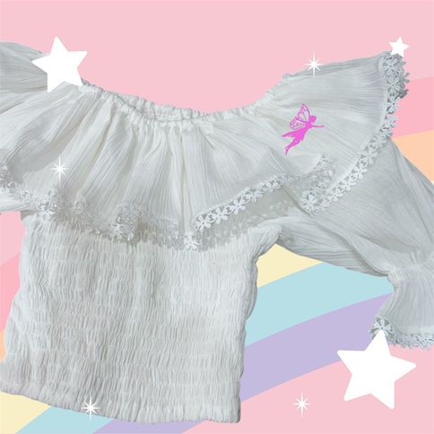 White off-shoulder shirt with long sleeves and lacy details on colorful background.