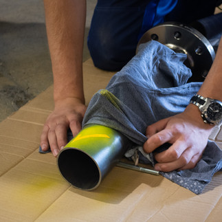 Ein Stahlrohr welches seitlich auf dem Boden liegt. Der untere Teil des Rohres ist mit einem Tuch abgedeckt. Der obere Teil ist gelb eingefärbt.