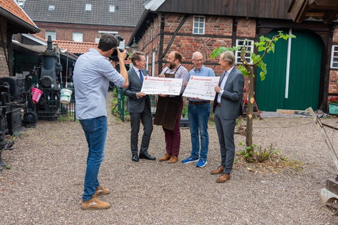 Vier Männer vor einer Scheune und ein Fotograf der sie fotografiert .