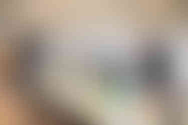 In einem Raum sieht man einen gedeckten Tisch. Im Hintergrund stehen mehrere Personen.