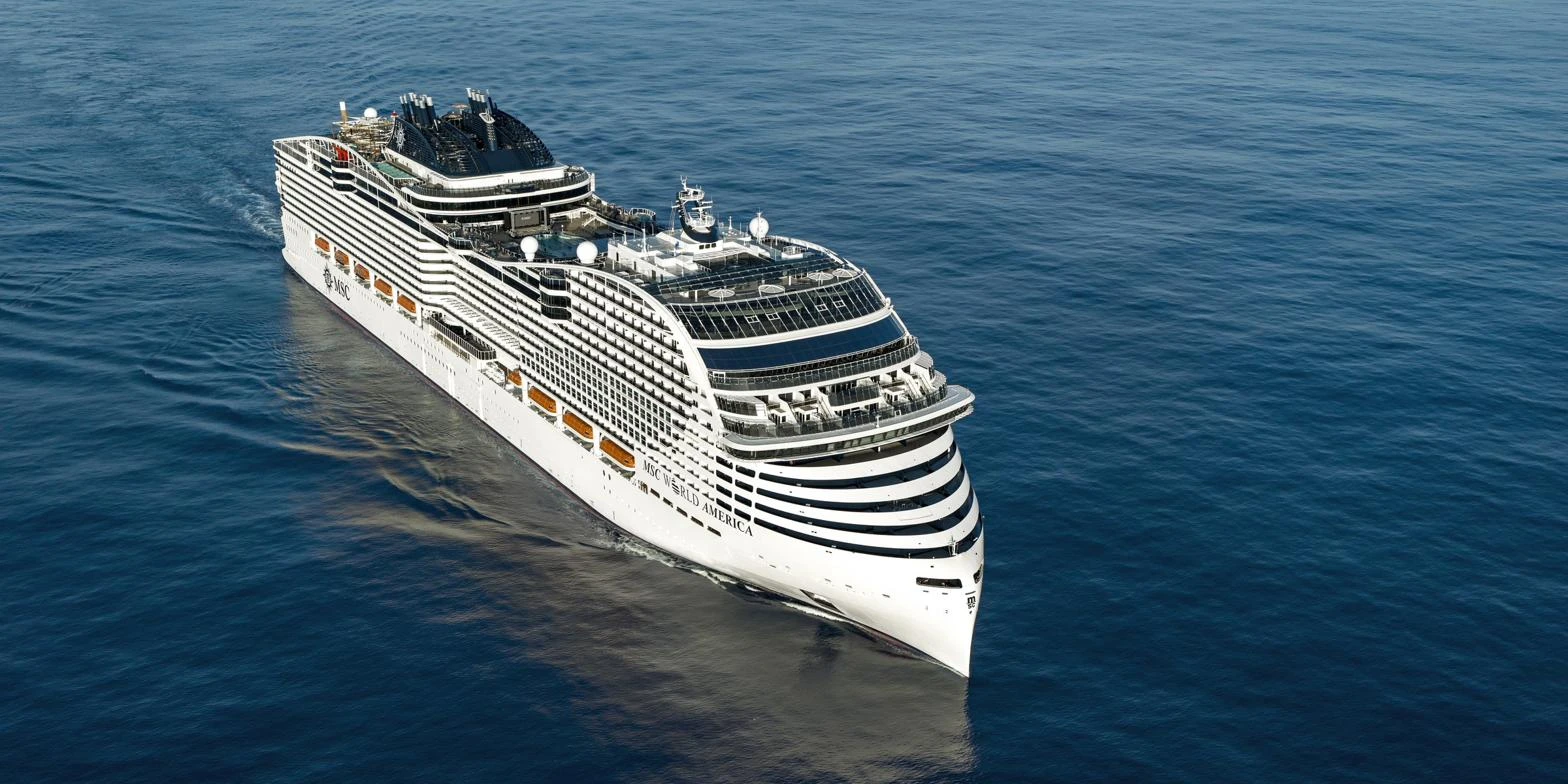 Cruise ship sailing across deep blue open ocean, seen from above