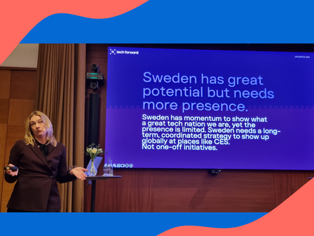 Woman in a suit, large screen with text.