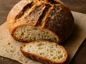 Einfaches Bauernbrot mit goldbrauner Kruste auf einem Holzbrett, angeschnitten.