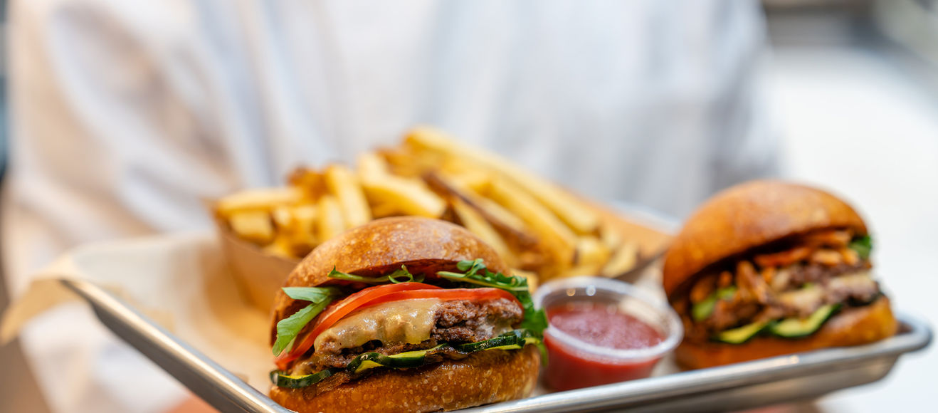a chef holds a tray of cheeseburgers and fries from Mom's List.