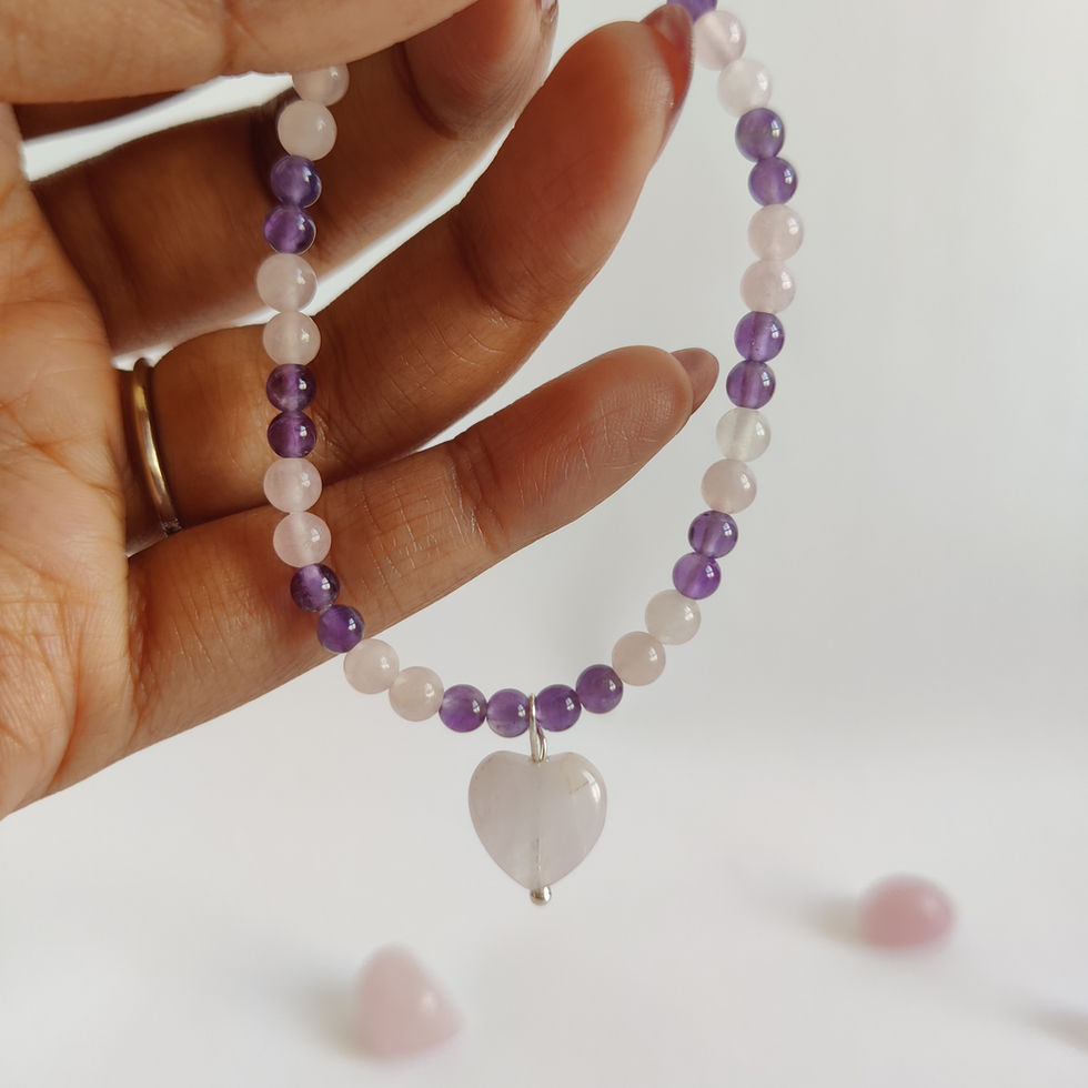 Close-up of a delicate pink Rose Quartz bead bracelet with purple Amethyst accent stones and a small heart charm.