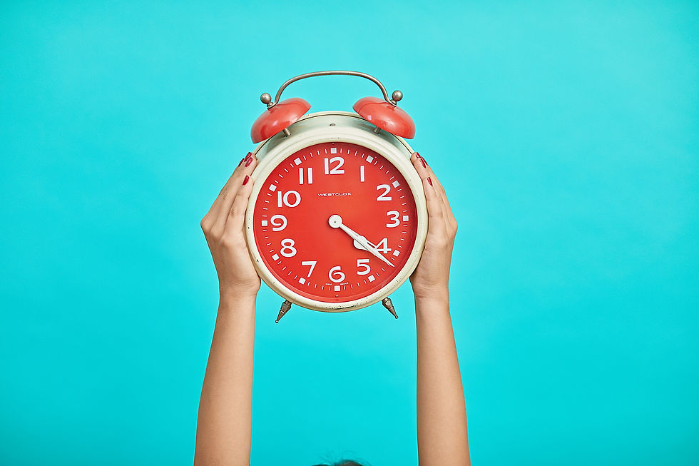 two arms thrusting up from the bottom of the frame. The hands hold a large old school alarm clock. 