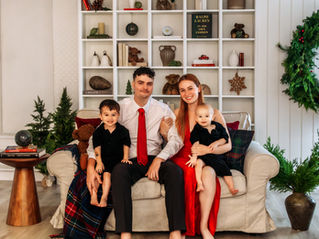Family sitting on the couch in front of christmas decor for photos.