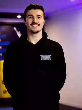 Fred Pace, instructor at Mozhdeh Martial Arts, smiling in a black MMA hoodie inside the training facility