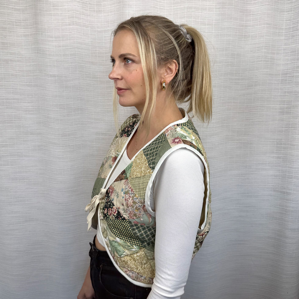 Side view of green patchwork quilted vest showing cropped fit