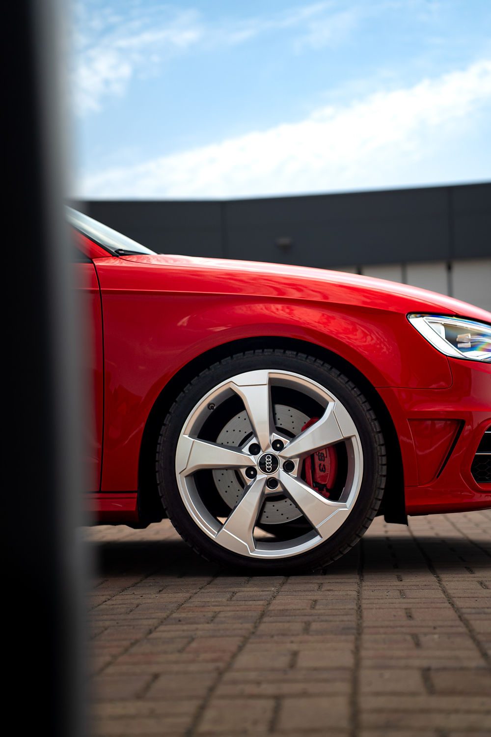Červené auto, detail kola a brzdového třmenu.
