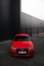 Červené Audi s českou SPZ před tmavou budovou