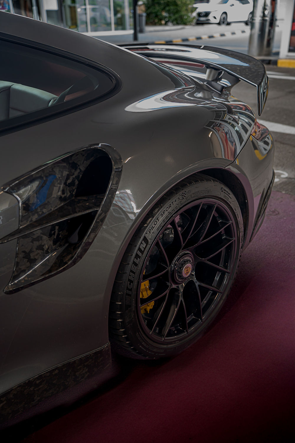 Šedý sportovní vůz, detail zadního kola a žlutých brzd