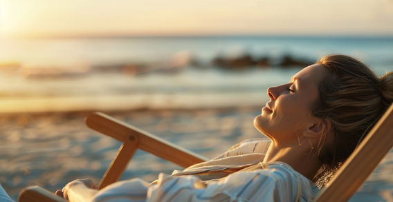 Woman enjoying sunshine while relaxing on beach chair near the ocean MINDCLARITYretreats