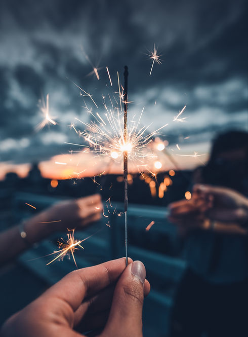 Someone holding a lit sparkler against a dark sky
