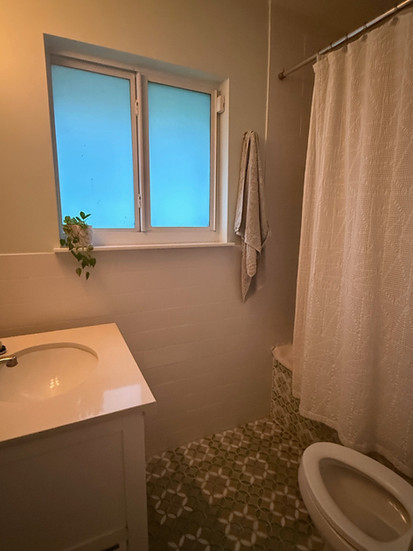 sideview of a white bathroom sink window and tile