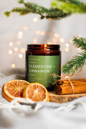 Christmas candle product photography with fairy lights, christmas tree, oranges and cinnamon sticks