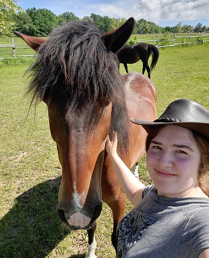 Anna steht lächelnd neben einem Pferd