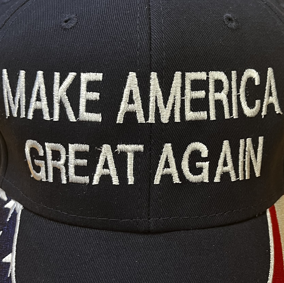 Detail view of MAGA hat with American flag embroidered brim and white block lettering on a navy blue crown.