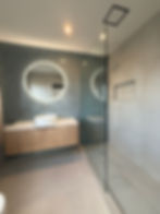 Bathroom renovation with round LED mirror and glass shower screen in Wattle Farms, Auckland
