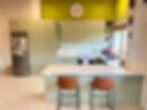 Finished sage green kitchen with white island, bar stools and mustard feature wall by Sorted Home Solutions