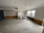 Garage or utility room with exposed wall framing around the perimeter and a bare concrete floor mid-renovation